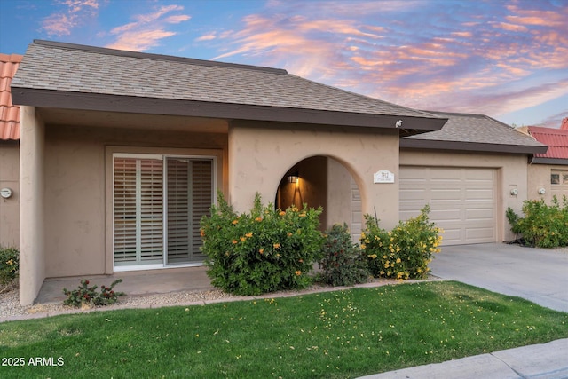 view of front of house with a garage, driveway, a shingled roof, a front lawn, and stucco siding