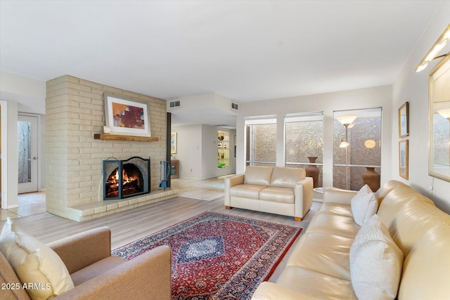 living area with light wood-type flooring, a fireplace, and visible vents