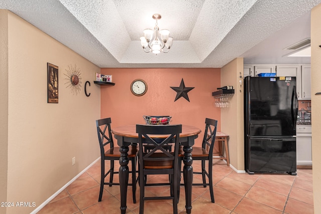 tiled dining space featuring a tray ceiling, a textured ceiling, and a notable chandelier