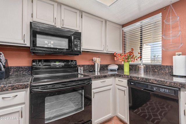 kitchen featuring black appliances, white cabinets, light tile patterned floors, and dark stone countertops