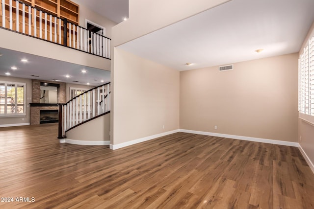 unfurnished living room with a stone fireplace and wood-type flooring