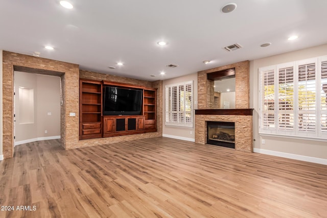 unfurnished living room with a stone fireplace and light wood-type flooring