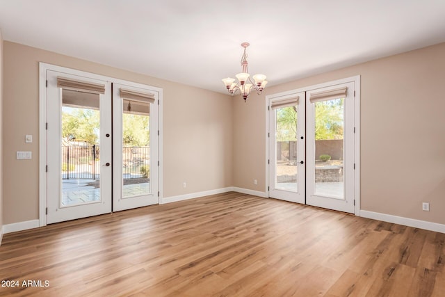 interior space featuring french doors, an inviting chandelier, and light wood-type flooring