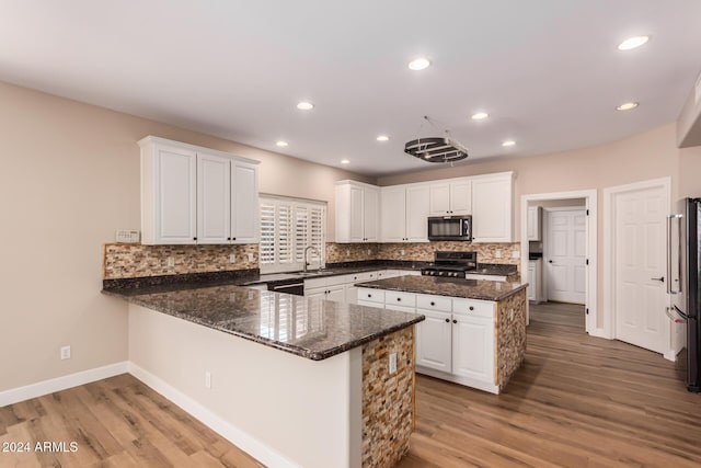 kitchen featuring kitchen peninsula, light wood-type flooring, white cabinetry, and stainless steel appliances