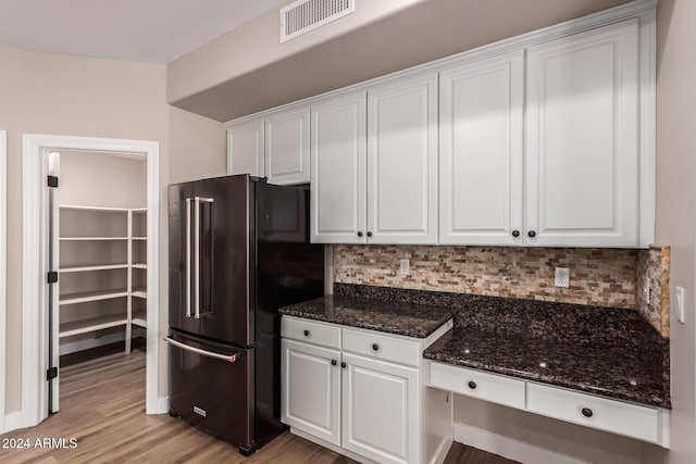 kitchen with light hardwood / wood-style floors, white cabinetry, high quality fridge, and dark stone counters