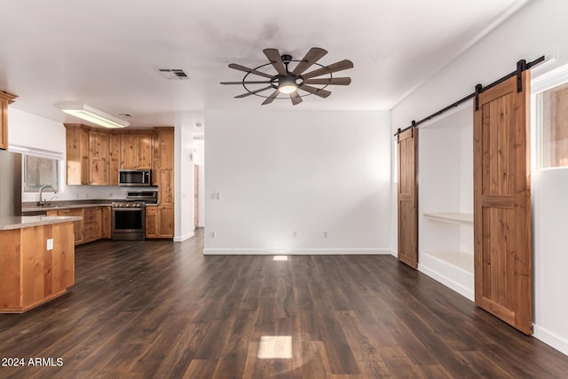 kitchen featuring a barn door, sink, dark wood-type flooring, and appliances with stainless steel finishes