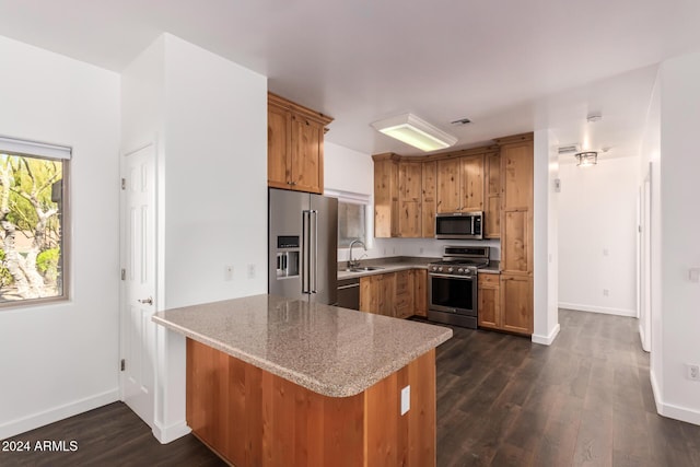 kitchen featuring sink, light stone countertops, dark hardwood / wood-style flooring, kitchen peninsula, and stainless steel appliances