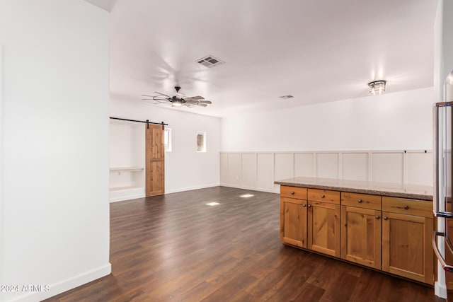 interior space featuring light stone countertops, dark hardwood / wood-style flooring, a barn door, and ceiling fan