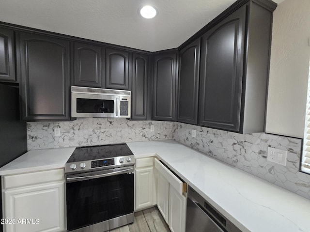 kitchen with light stone counters, stainless steel appliances, light wood-style floors, and decorative backsplash