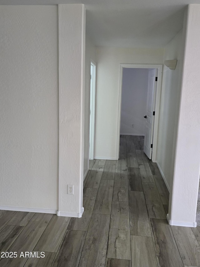 hall with baseboards, wood finished floors, and a textured wall