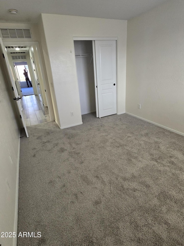 unfurnished bedroom with a closet, baseboards, visible vents, and carpet floors