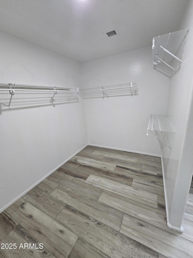 spacious closet featuring wood finished floors and visible vents