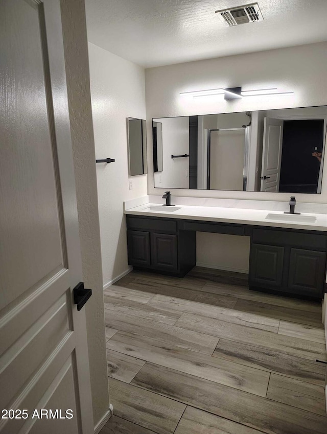 bathroom featuring double vanity, visible vents, wood finished floors, and a sink