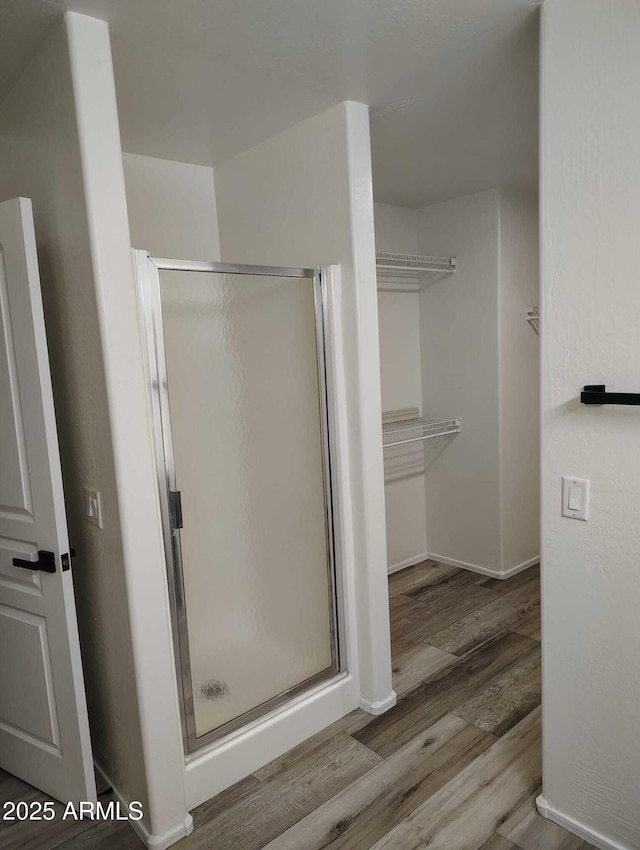 full bath with baseboards, wood finished floors, and a shower stall