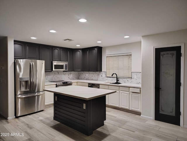 kitchen with visible vents, a sink, stainless steel appliances, light countertops, and backsplash