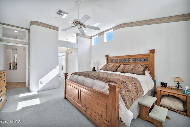 bedroom with ceiling fan, light colored carpet, and connected bathroom