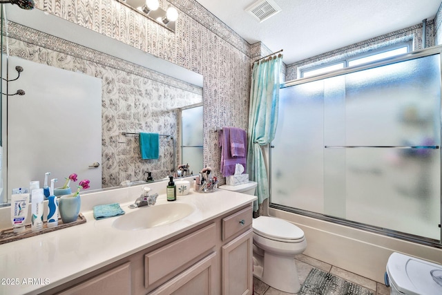 full bathroom featuring shower / bath combination with glass door, tile patterned flooring, vanity, a textured ceiling, and toilet