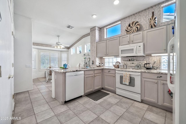 kitchen featuring lofted ceiling, white cabinets, kitchen peninsula, light stone countertops, and white appliances