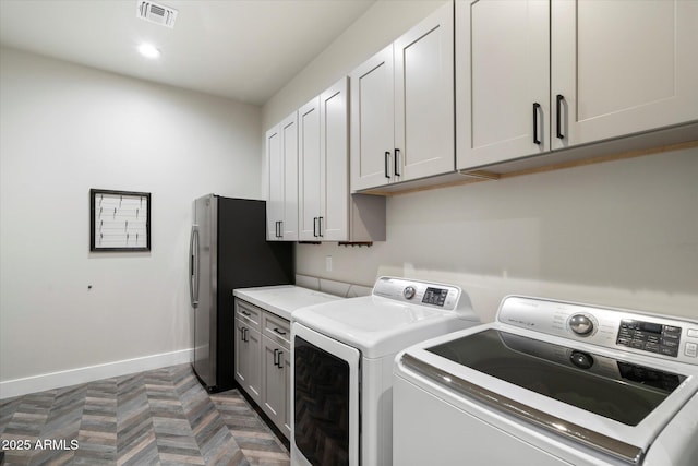 laundry room featuring washing machine and dryer, cabinets, and dark parquet flooring