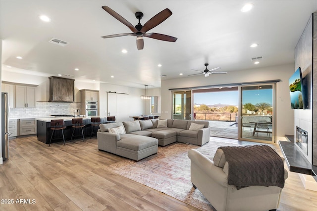 living room with ceiling fan, light hardwood / wood-style floors, and sink