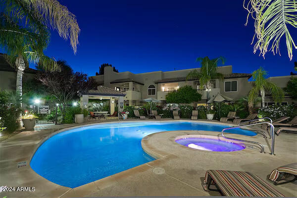 pool at night with a community hot tub and a patio area