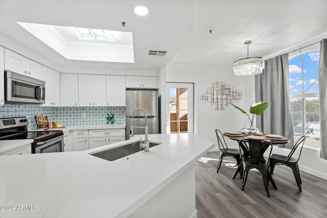 kitchen featuring sink, decorative light fixtures, decorative backsplash, white cabinets, and appliances with stainless steel finishes