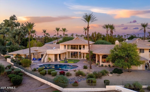 back house at dusk with a pool with hot tub and a patio area