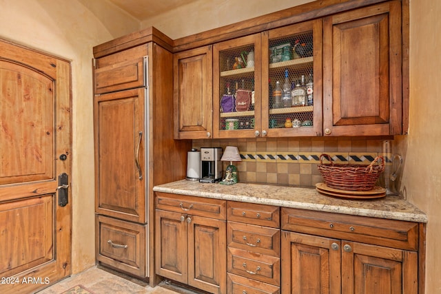 bar with light stone countertops, tasteful backsplash, and light tile floors