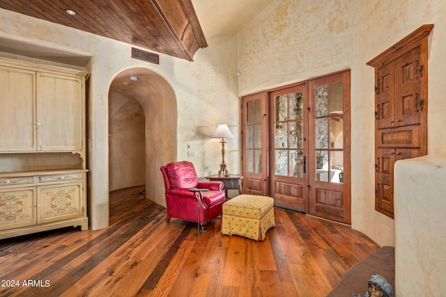 living area with a towering ceiling and dark hardwood / wood-style flooring