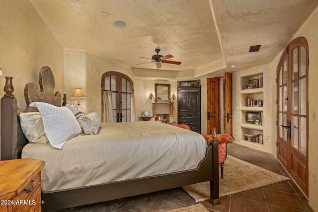 bedroom featuring dark tile flooring, french doors, a raised ceiling, and ceiling fan