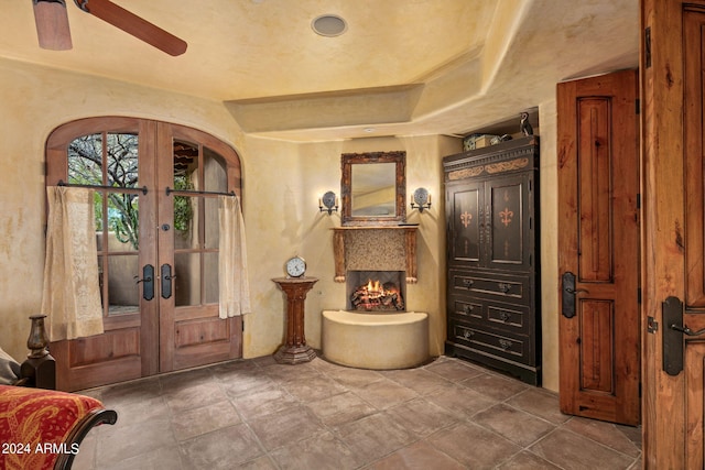 foyer entrance with french doors, dark tile floors, and ceiling fan