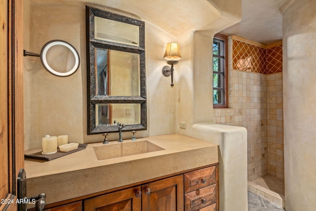 bathroom with oversized vanity and tiled shower