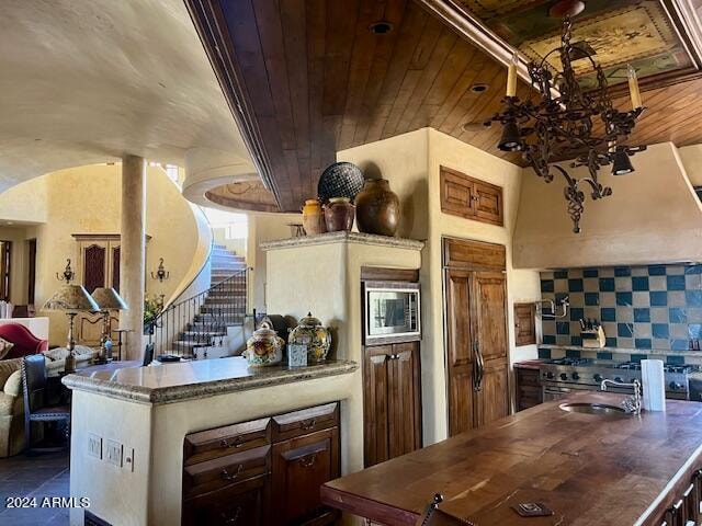 kitchen with an inviting chandelier, backsplash, built in appliances, extractor fan, and wood ceiling