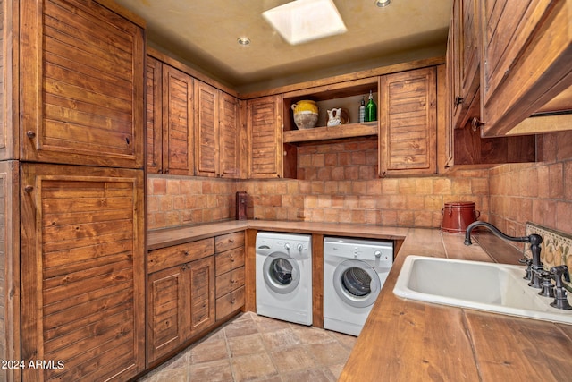 washroom featuring light tile floors, sink, cabinets, and washing machine and clothes dryer