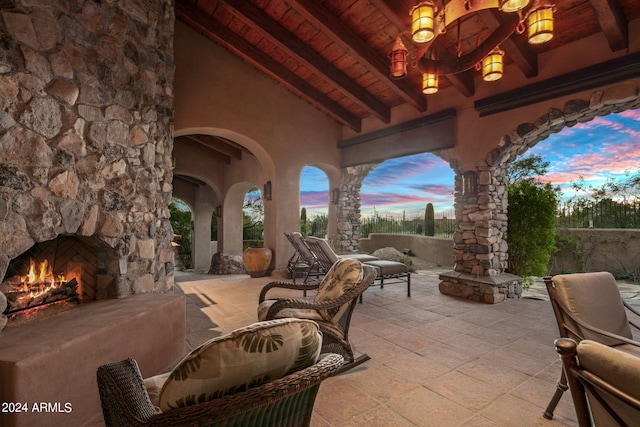 patio terrace at dusk featuring an outdoor stone fireplace