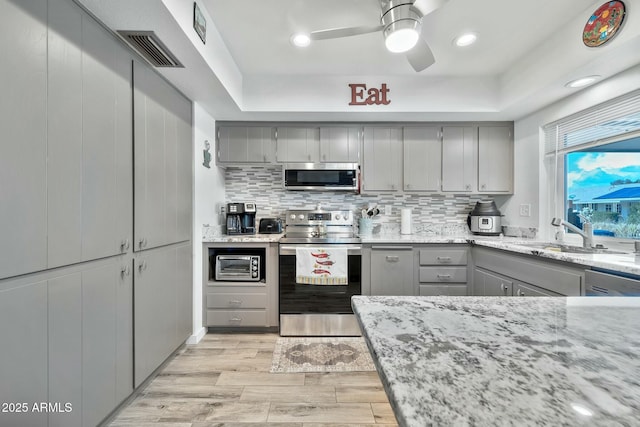 kitchen with sink, backsplash, gray cabinets, and stainless steel appliances