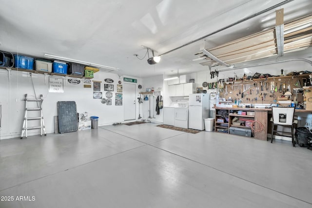 garage with white refrigerator, a garage door opener, washer and clothes dryer, and a workshop area