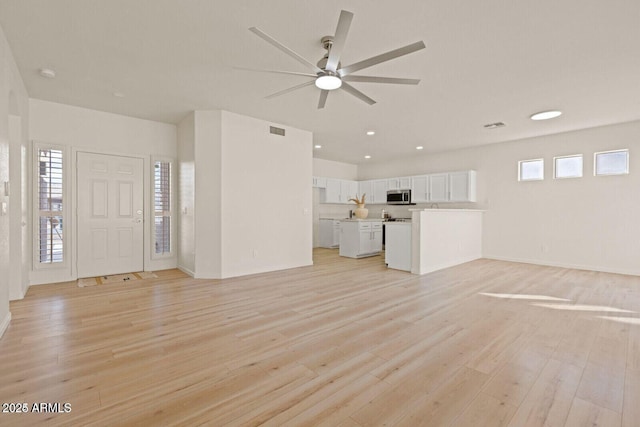 unfurnished living room featuring a ceiling fan, visible vents, and light wood finished floors