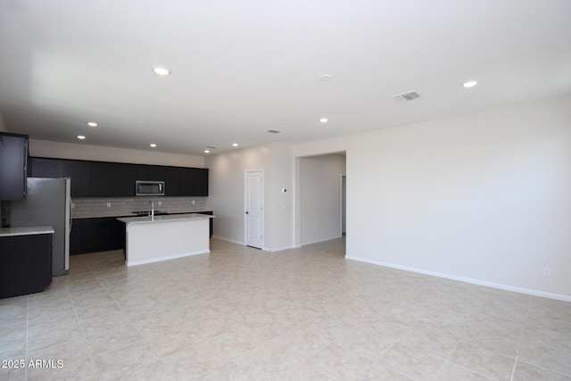 17419 W Via De Luna Dr, Surprise, AZ 85387 - kitchen with appliances with stainless steel finishes, dark cabinetry, open floor plan, light countertops, and an island with sink