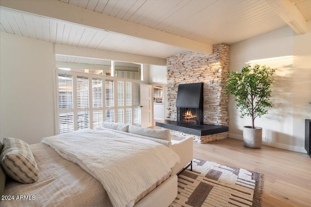 bedroom featuring a fireplace, beam ceiling, wooden ceiling, and light wood-type flooring