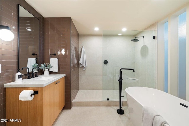 bathroom with vanity, independent shower and bath, and tile walls