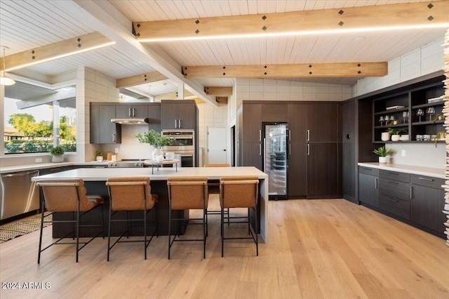 kitchen featuring a breakfast bar, wood ceiling, stainless steel appliances, dark brown cabinetry, and light hardwood / wood-style flooring