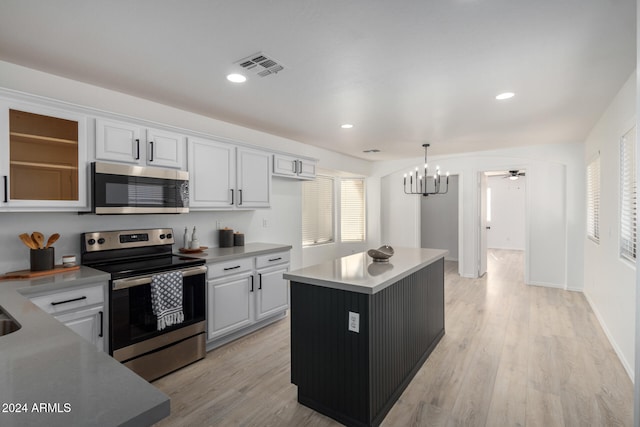 kitchen featuring stainless steel appliances, a center island, light hardwood / wood-style floors, white cabinetry, and hanging light fixtures