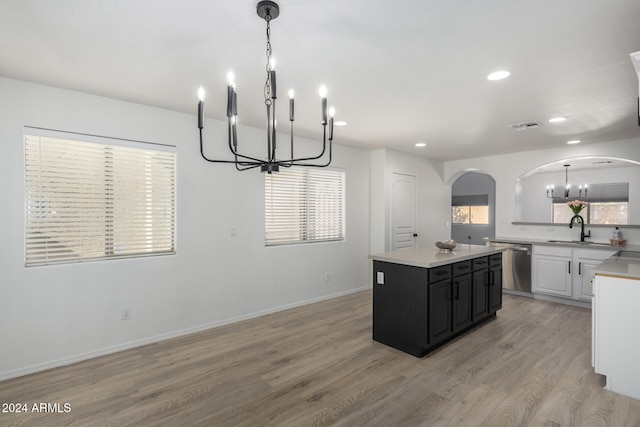 kitchen with light wood-type flooring, stainless steel dishwasher, a kitchen island, sink, and white cabinetry