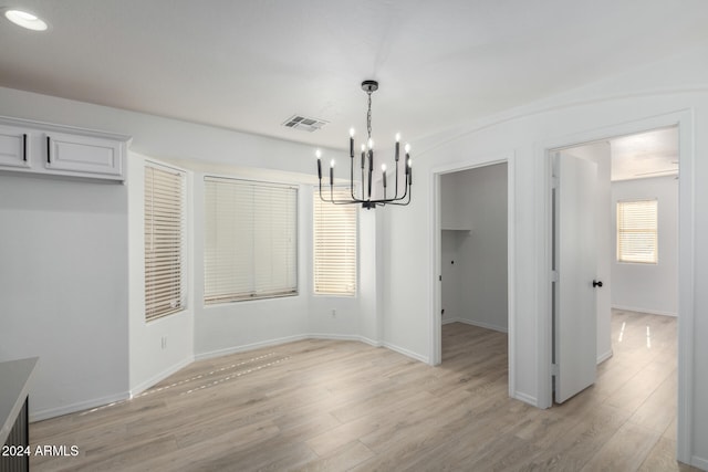 unfurnished dining area with light hardwood / wood-style floors and a notable chandelier