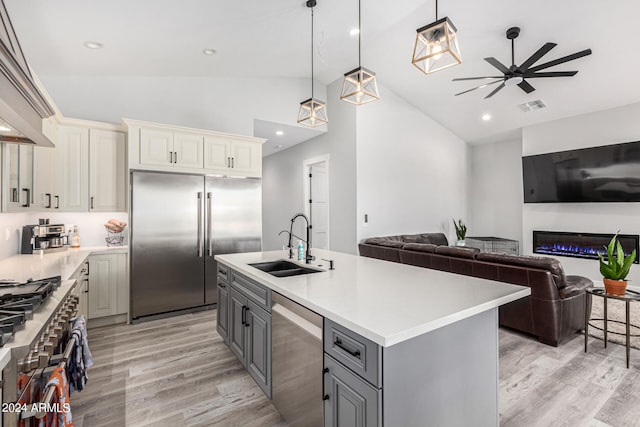 kitchen with an island with sink, sink, light wood-type flooring, premium appliances, and gray cabinets