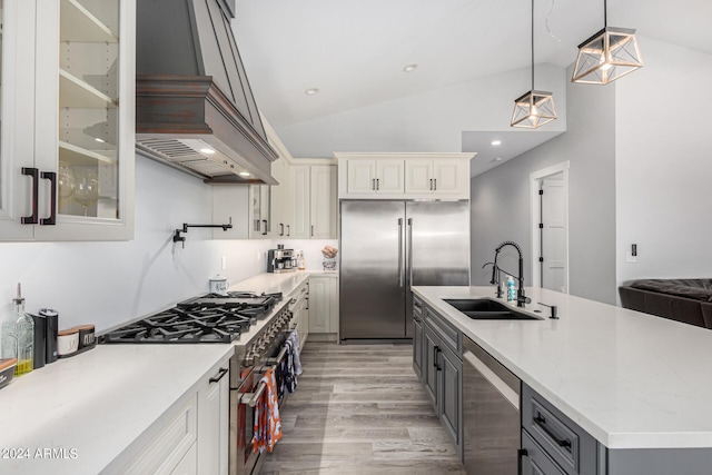 kitchen featuring vaulted ceiling, pendant lighting, gray cabinets, sink, and premium appliances