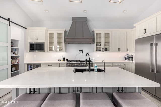 kitchen with a large island with sink, stainless steel appliances, a breakfast bar area, and custom exhaust hood