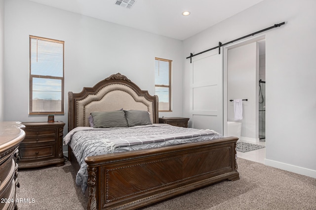 carpeted bedroom featuring ensuite bath, multiple windows, and a barn door