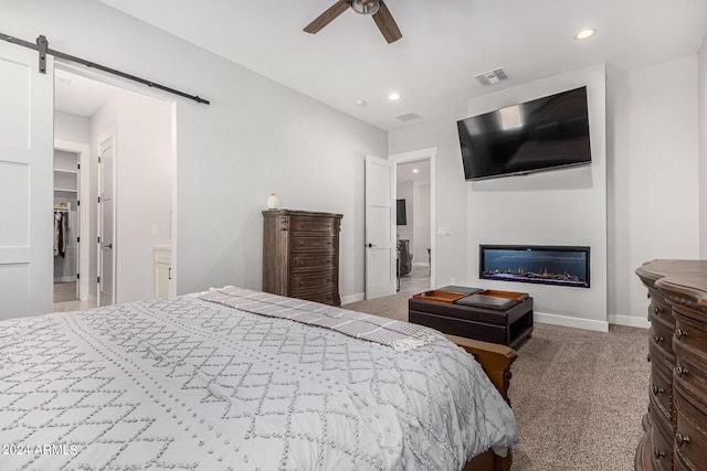 carpeted bedroom featuring ceiling fan, ensuite bath, and a barn door